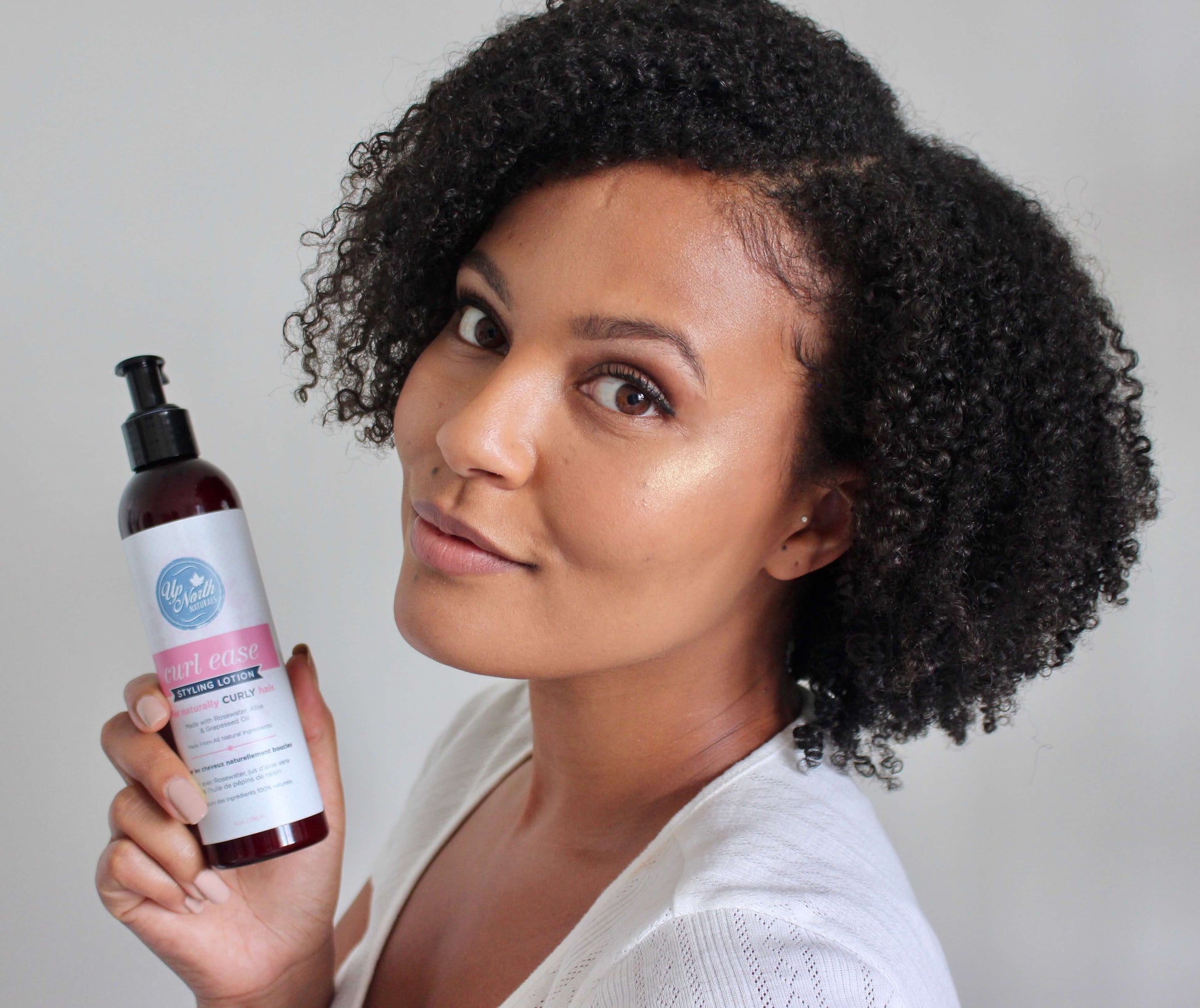 Woman with beautiful naturally curl hair holding curl ease styling lotion